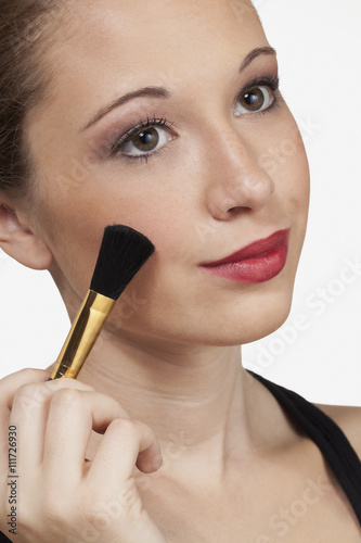 teen model head shot brushes on makeup.