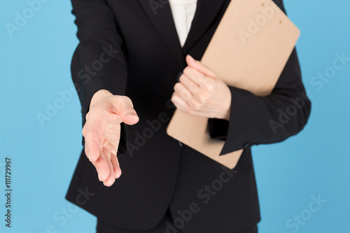 portrait of asian businesswoman shaking hand isolated on blue background