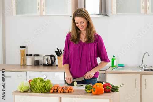 Woman Cutting Vegetable In Kitchen