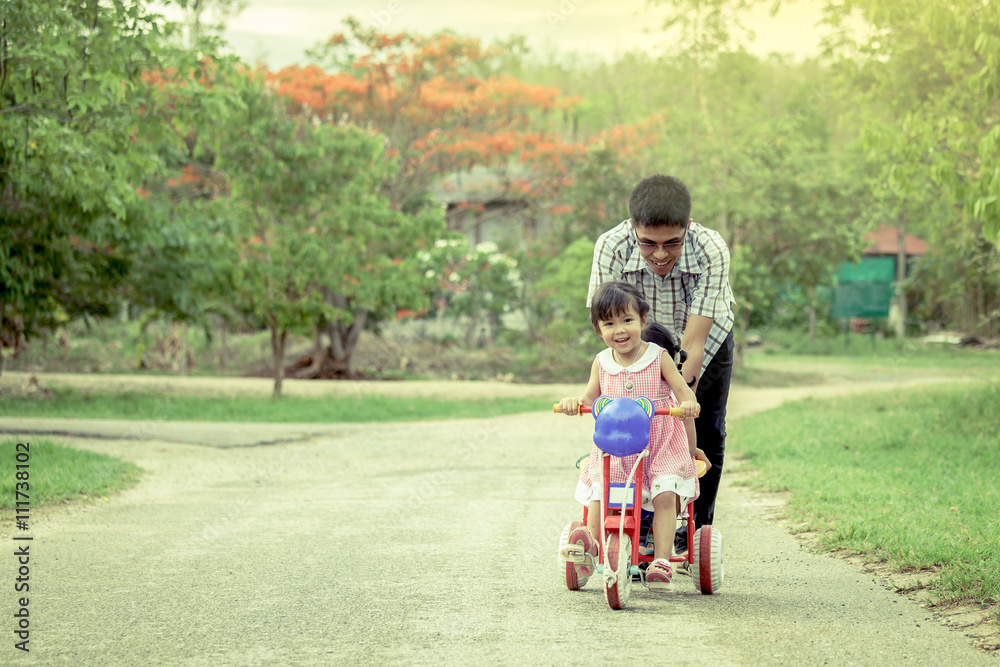 Child little girl having fun to ride tricycle with family Child little girl having fun to ride tricycle with family