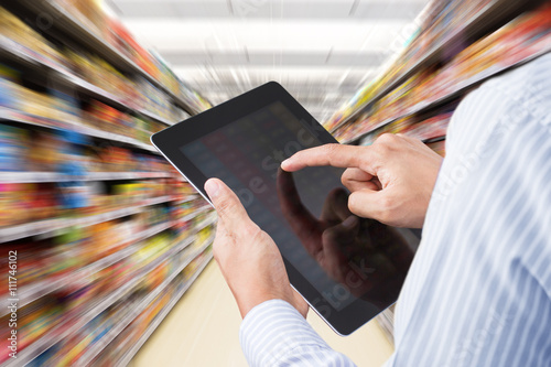 Businessman checking inventory in supermarket on touchscreen tablet. Motion blur Background photo