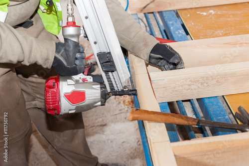 Building a wall for frame house.Worker use Framing Nailer to attach wooden beams photo