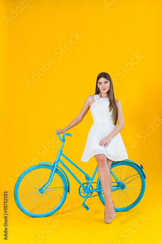 Beautiful young woman posing seated on a blue bicycle © fotofabrika