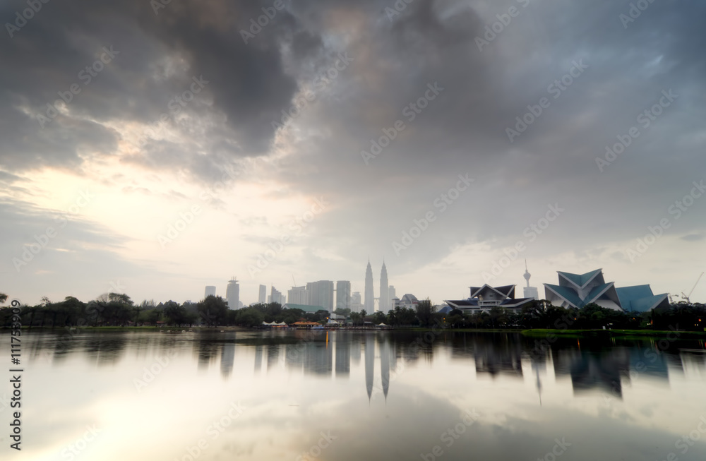 blurred image backgroud of Kuala Lumpur City with reflection on the lake and dramatic cloud