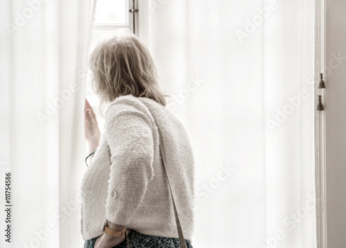 Kvinna tittar ut genom ett fönster