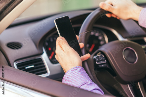  close up of young man hand with smartphone driving car