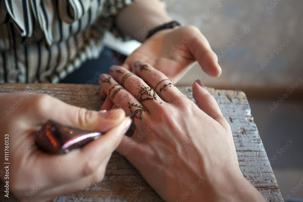 Artist applying henna tattoo on women hands. Mehndi is tradition