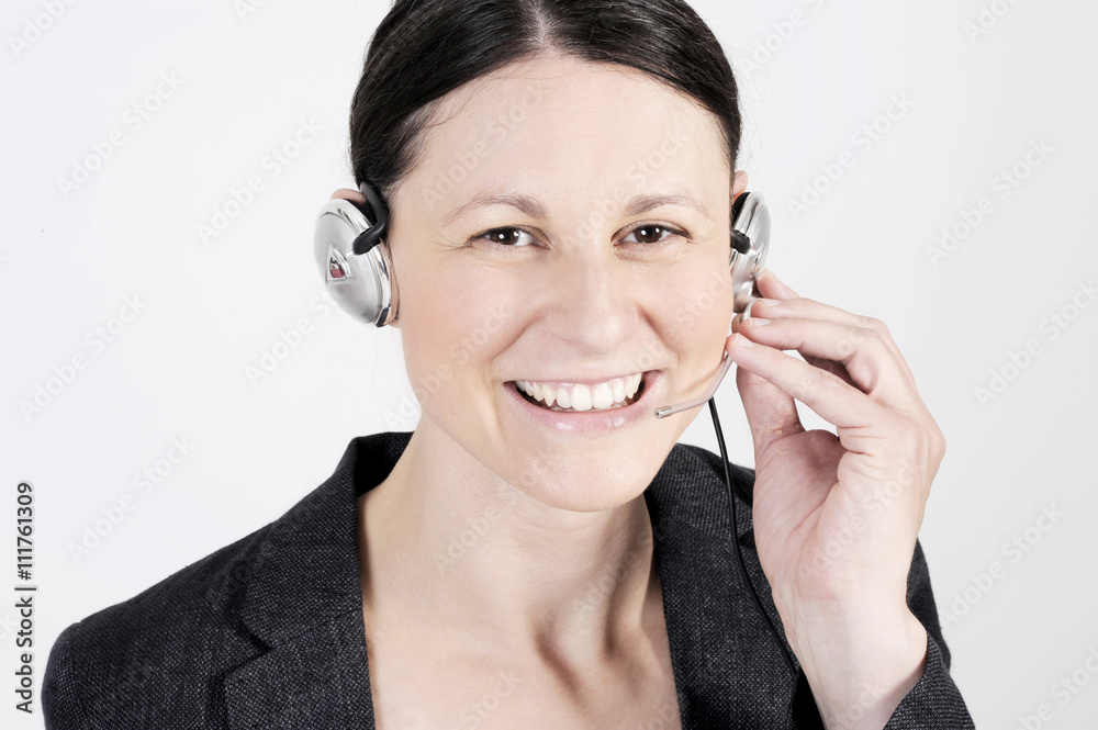 Pretty friendly officer woman with headset in a call center smiling and speaking with the client. Pretty friendly officer woman with headset in a call center smiling and speaking with the client.