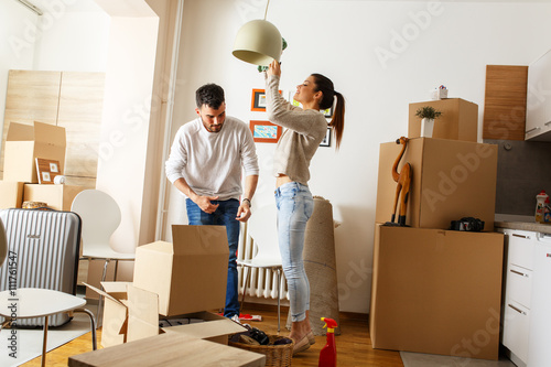 Young married couple cleaning and selecting furniture and accessories in their new home. Moving house. 