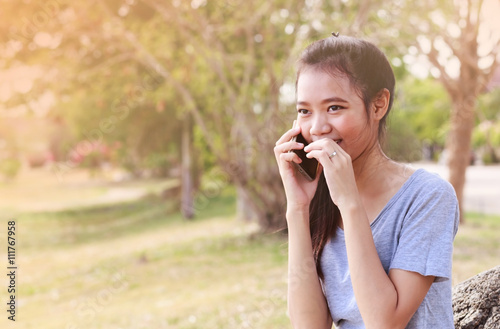 Asian woman sitting on stone using a mobile telephone