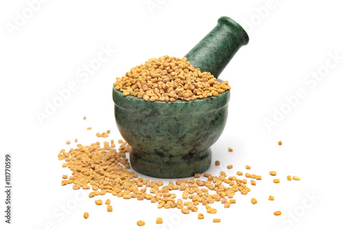 Organic Fenugreek (Trigonella foenum-graecum) on marble pestle and white background. photo
