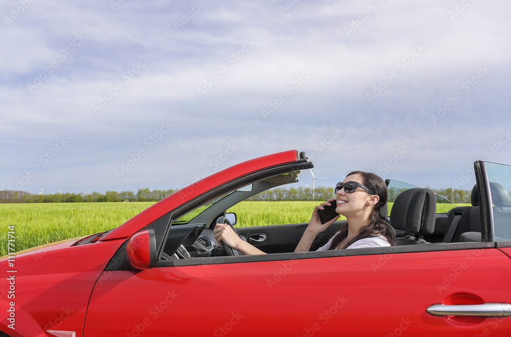 Woman drives the car and talking on the phone.