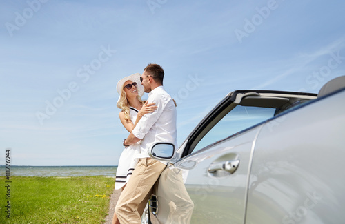 happy couple hugging near cabriolet car at sea