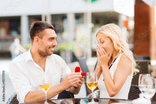 happy couple with engagement ring and wine at cafe