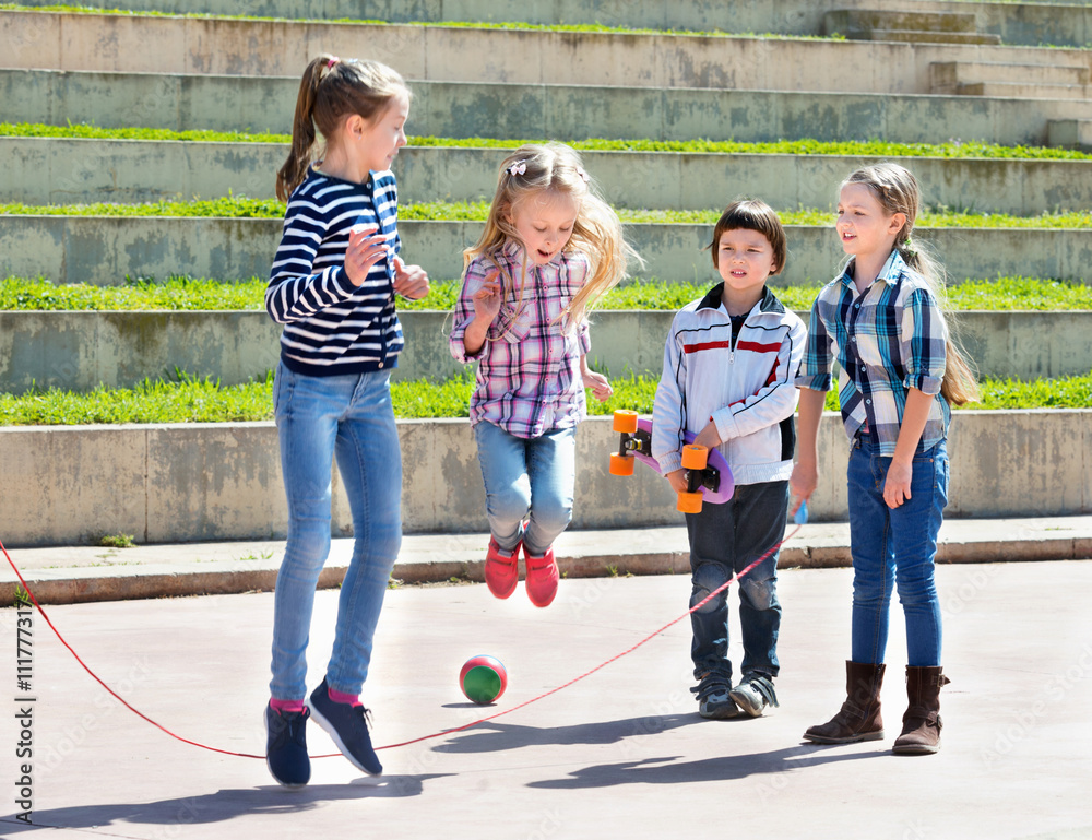 Children playing skipping rope jumping game foto de Stock Adobe Stock