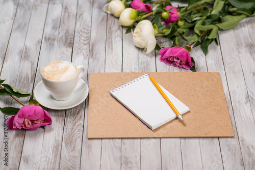 Fototapeta Naklejka Na Ścianę i Meble -  Notebook with a pencil next to coffee and peonies flowers on wooden background.