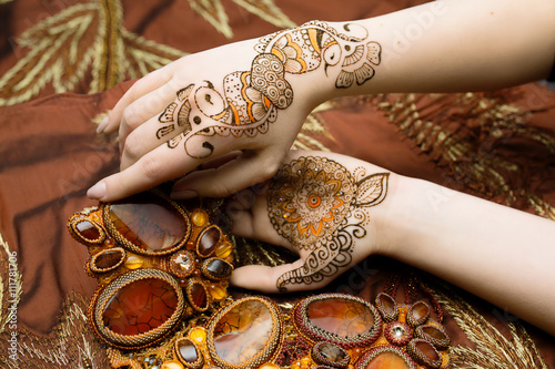 Two womans hands mehendi picture orange bright fabric with pleats