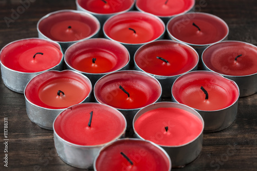 Many extinguished small red candles closeup on wooden table
