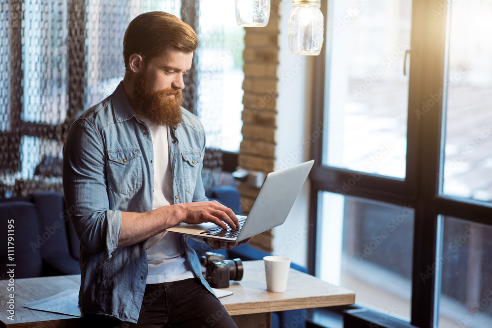 Pleasant bearded man standing with laptop Pleasant bearded man standing with laptop