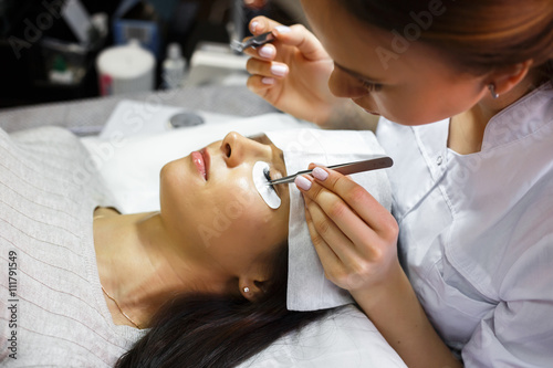eyelash extension procedure - master and a client in a beauty salon