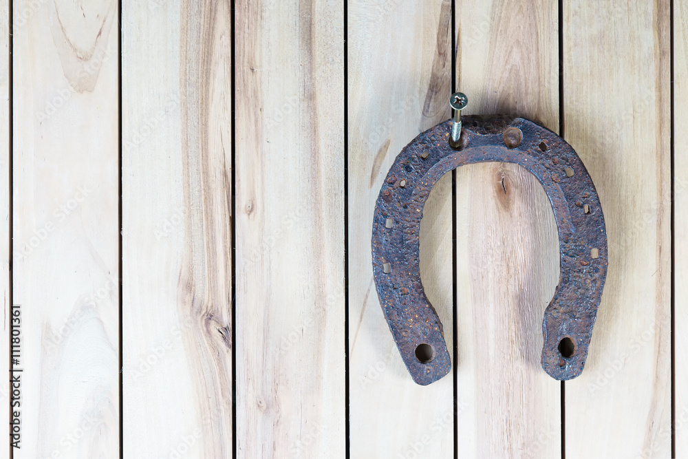 Old rusty horseshoe hanging on a wooden background Old rusty horseshoe hanging on a wooden background