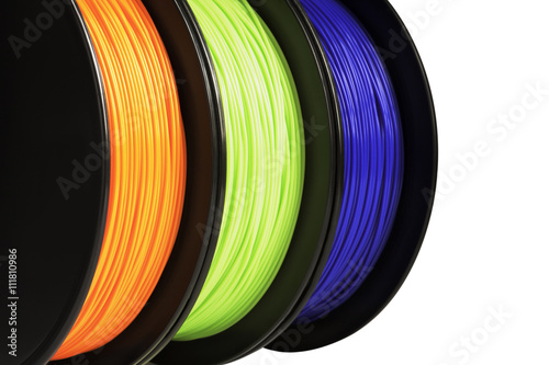Filament for 3d printing. Bright termoplastic of neon orange, green and blue colors. Isolated on white background. Material produced from polylactic (pla) acid. Three reels vertical view. Macro photo