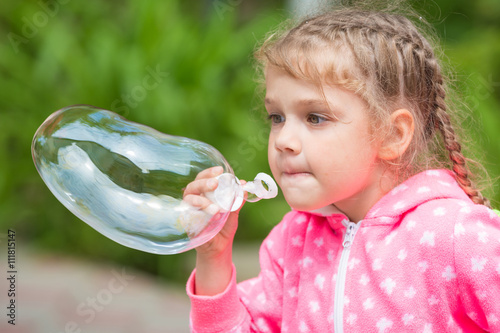 Five-year girl inflates a large soap bubble