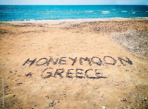 Honeymoon in Greece written on sandy beach near the sea