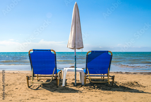 Fototapeta Naklejka Na Ścianę i Meble -  Empty lounge chairs with sun umbrella on sandy beach