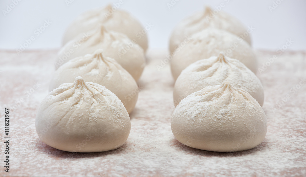 Fashioned khinkali lie on a wooden board sprinkled with flour. Fashioned khinkali lie on a wooden board sprinkled with flour.