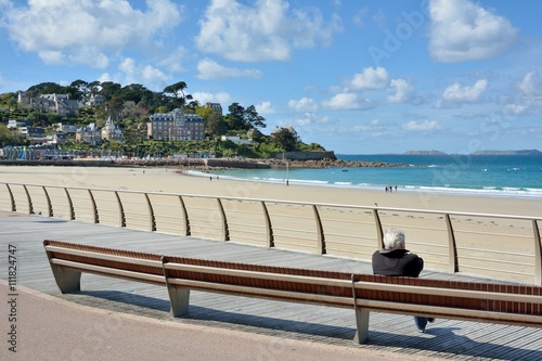 Schilderij op canvas Un retraité assis sur un banc face à la mer et la plage de Perros-Guirec en Bret