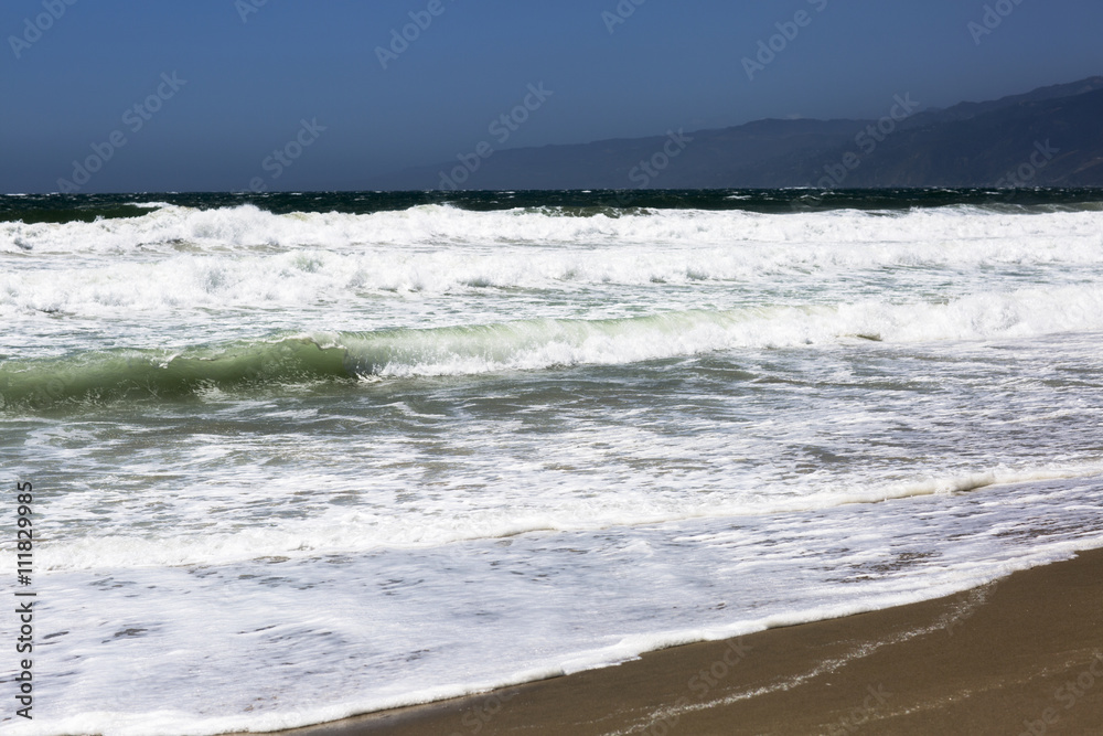 The waves of the Pacific ocean, the beach landscape. The ocean, mountains and blue sky in USA, Santa Monica. The ocean and waves during strong winds in United States, Santa Monica. The waves of the Pacific ocean, the beach landscape. The ocean, mountains and blue sky in USA, Santa Monica. The ocean and waves during strong winds in United States, Santa Monica.