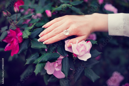Woman hand with french french manicure and ring on roses flowers © Nick Starichenko