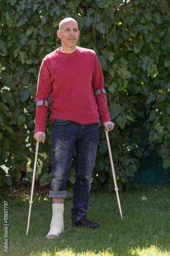 Young man with a leg cast in a garden