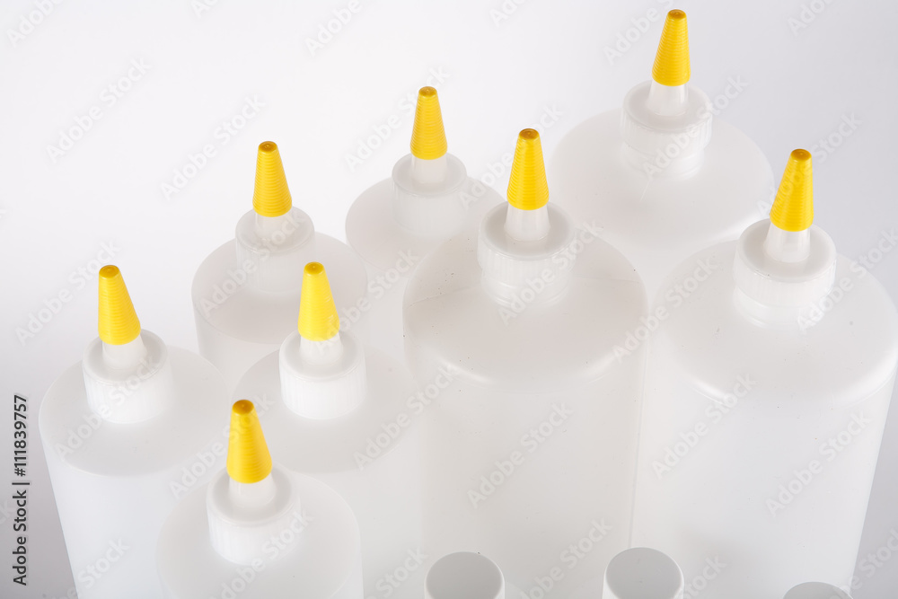 Close up white bottles with yellow caps on white background Close up white bottles with yellow caps on white background