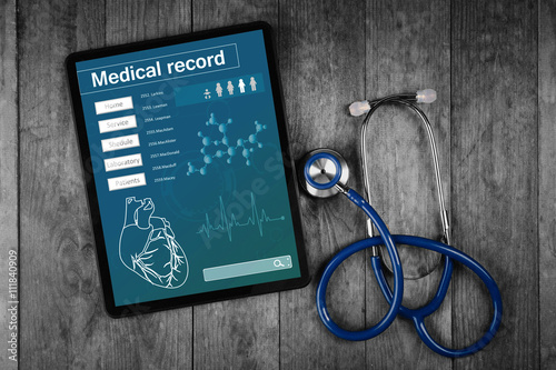 Medical record on tablet screen with stethoscope on wooden background