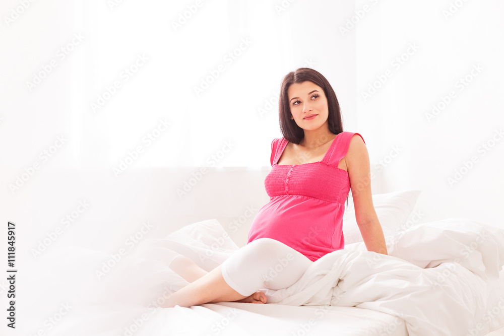 Beautiful pregnant lady is relaxing in bedroom Beautiful pregnant lady is relaxing in bedroom