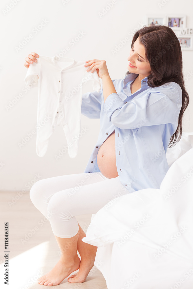 Beautiful expectant mother is showing small clothing Beautiful expectant mother is showing small clothing