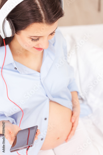 Cute pregnant woman is enjoying nice melody