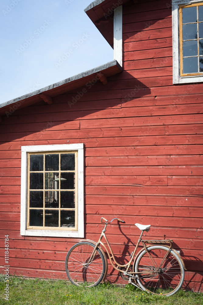 Vintage bicycle leaning against a red colored wooden house