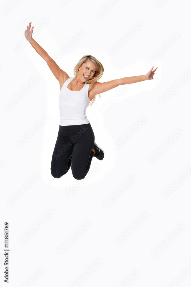 Beautiful blonde model in gym outfit jumps for joy, isolated on white