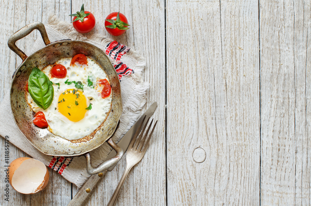 Fried egg with tomatoes and herbs n a old frying pan Fried egg with tomatoes and herbs n a old frying pan