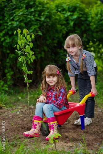 two girls ride in wheelbarrow