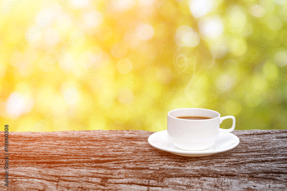 coffee cup on wooden table over abstract nature background.