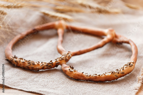 Fresh Pretzel with sunflower seeds on rustic background with spikelets. Pastries and bread in a bakery. Selective focus