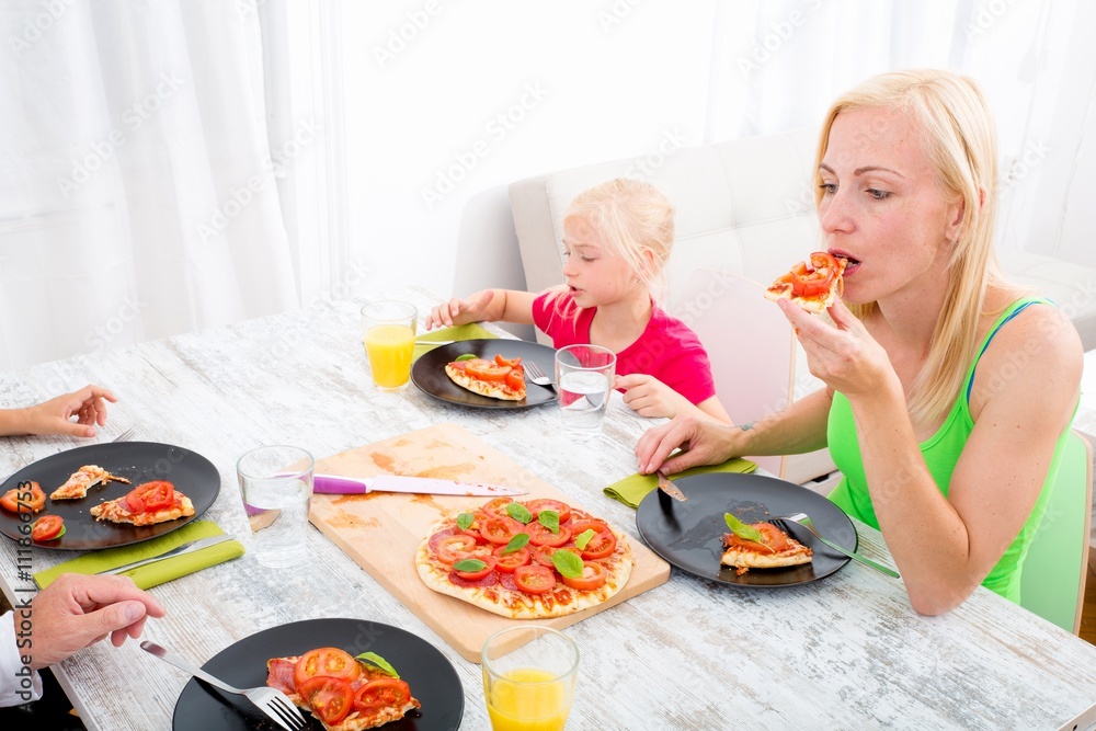 Father and mother with son and daughter eating Pizza for lunch or dinner..