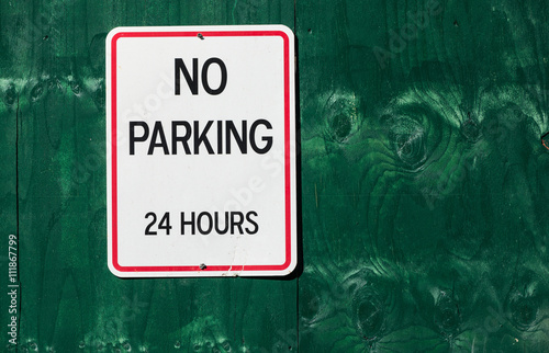 No parking 24 hours sign on grungy green wooden wall background