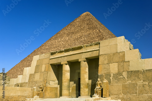 Egypt. Cairo - Giza. The entrance of the mastaba of Seshemnufer IV (late 5th Dynasty) and the Great Pyramid in background. The Pyramid Fields from Giza to Dahshur is on UNESCO World Heritage List