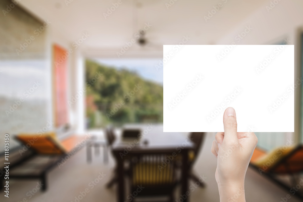 hand holding blank paper with interior background hand holding blank paper with interior background