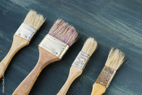 Paint brushes of various sizes on blue wooden background, diagonal composition